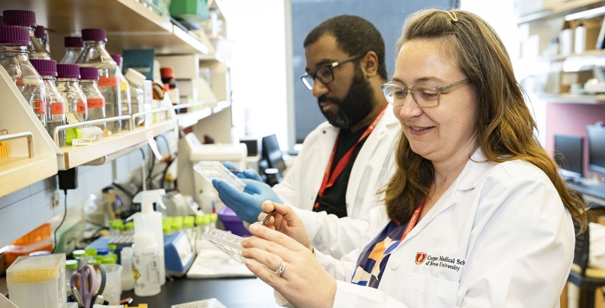 A photo of Amanda Fakira, PhD, assistant professor of biomedical sciences, working alongside  a student in the lab.