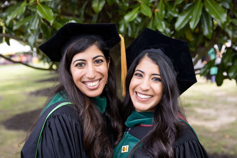 Two recent CMSRU graduates - and recent CMSRU alumni - pose for a photo in their regalia at a CMSRU Commencement ceremony.