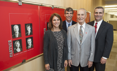 The Schlitt family stands in front of the Legacy Society Wall in the deans' suite at CMSRU.