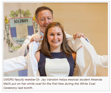 A photo of CMSRU faculty member Dr. Jay Vanston helps medical student Amanda Malik put on her white coat for the first time during the White Coat Ceremony.