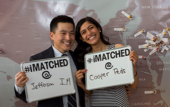 Two students stand holding their "I Matched" signs to showcase where they matched for their residency training.