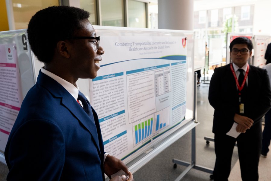 Two students stand with a poster showcasing their research project that they worked on during their time in the Premedical Urban Leaders Summer Enrichment (PULSE) program.