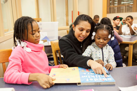 A CMSRU student poses with two children during an event that was part of the Primary Urban Partnership.