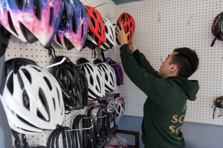 A CMSRU student is featured helping out with hanging bike helmets on a wall.