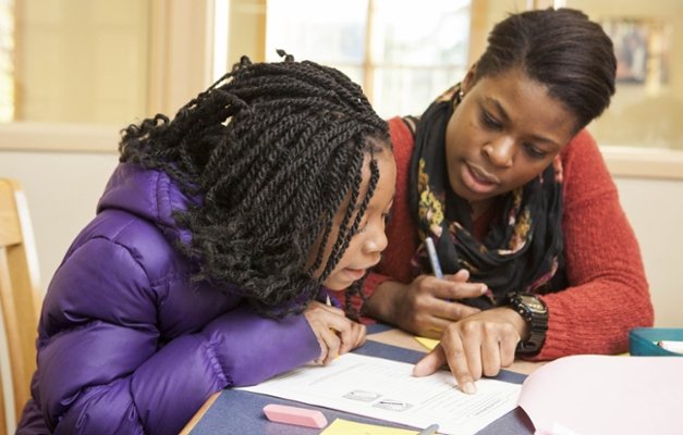 An adult helps a child with their homework.