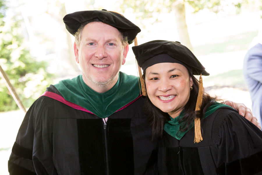 Two CMSRU faculty members pose for a photo in their regalia at a CMSRU Commencement ceremony.