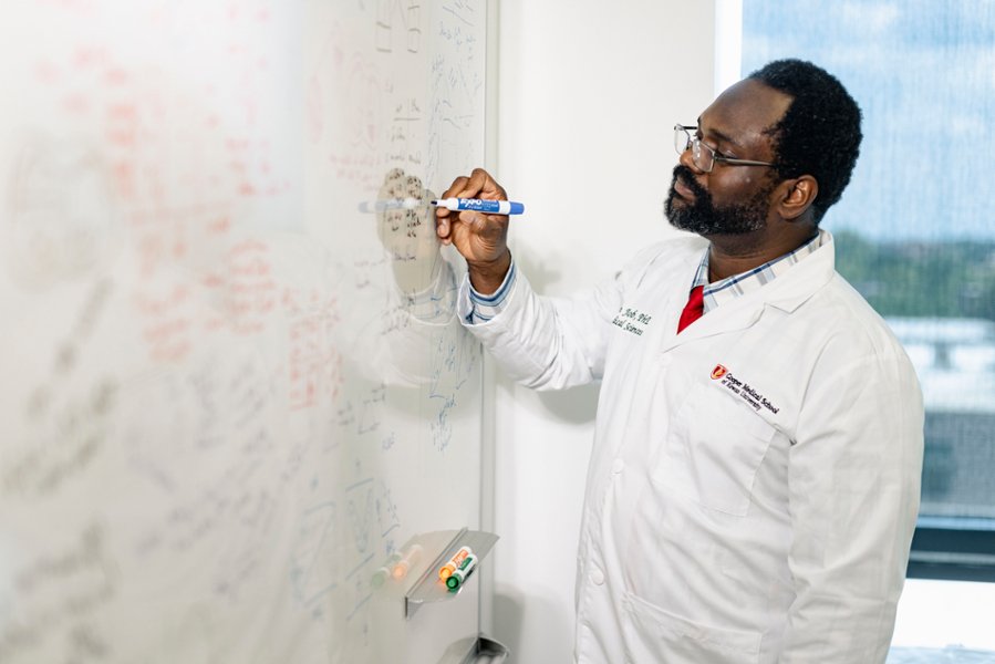 A photo of Martin Job, PhD, assistant professor of biomedical sciences at CMSRU, taking notes on a dry erase board.